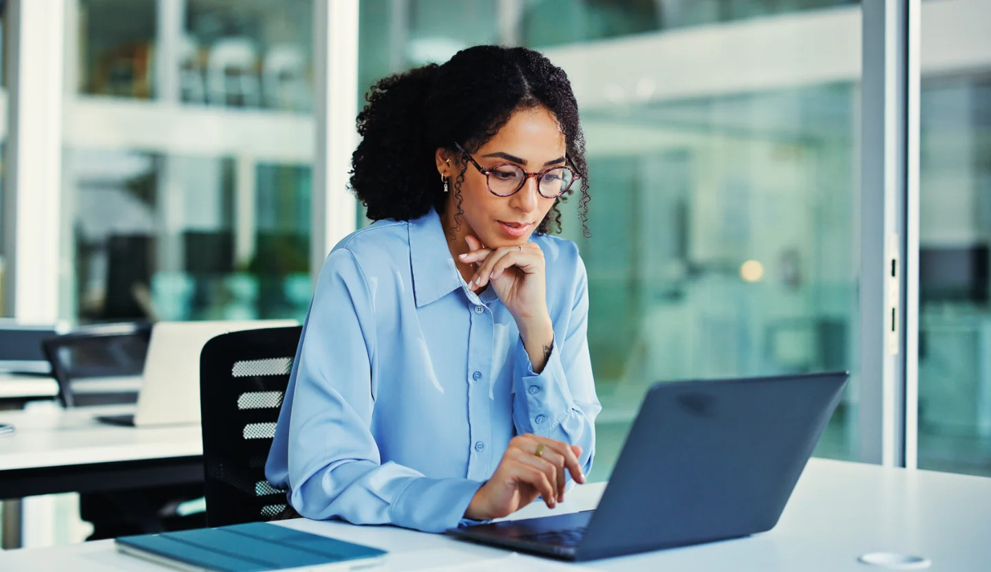 Office worker with glasses looks intently at a laptop