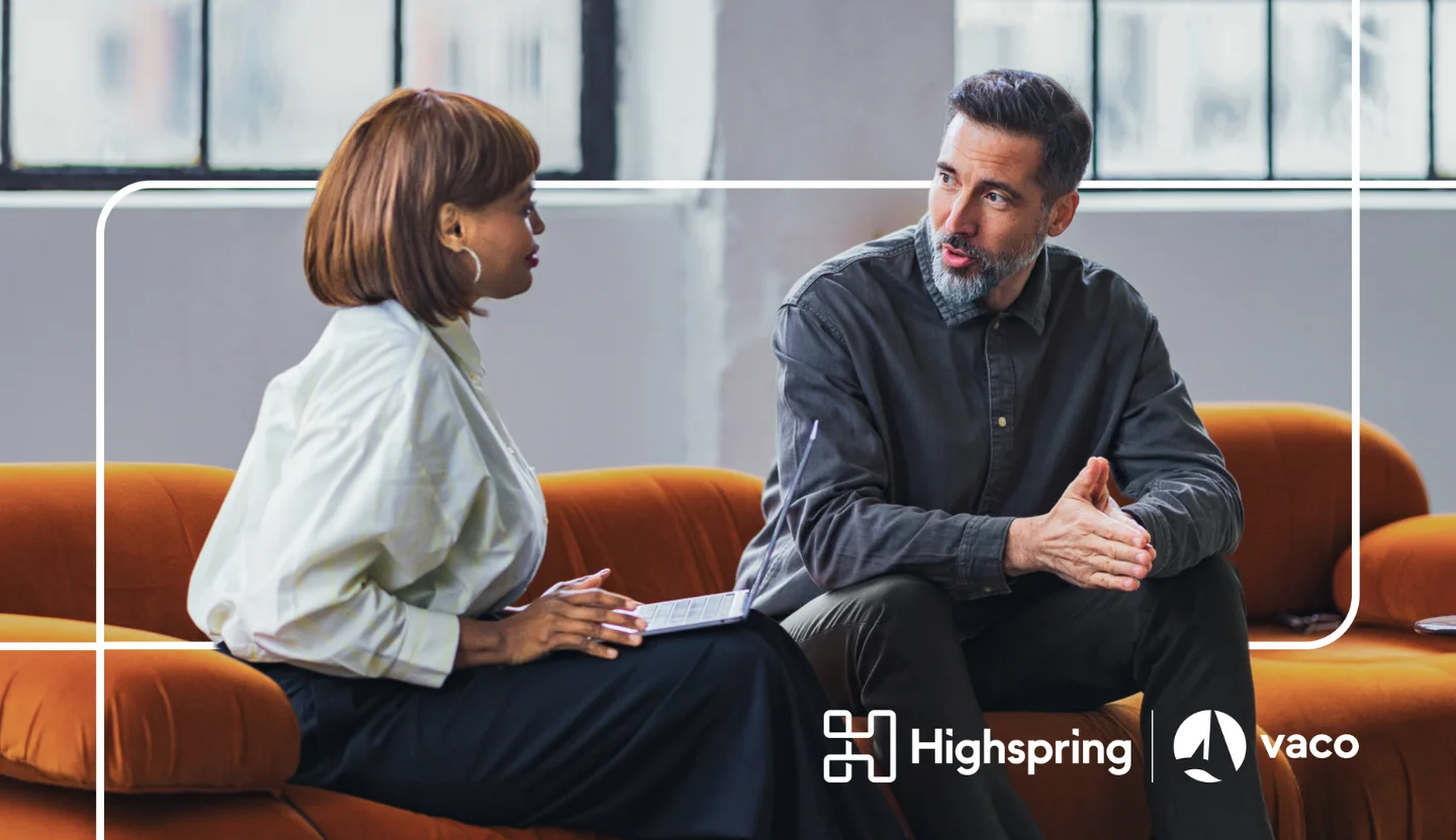 Two office workers have a conversation while sitting on a couch