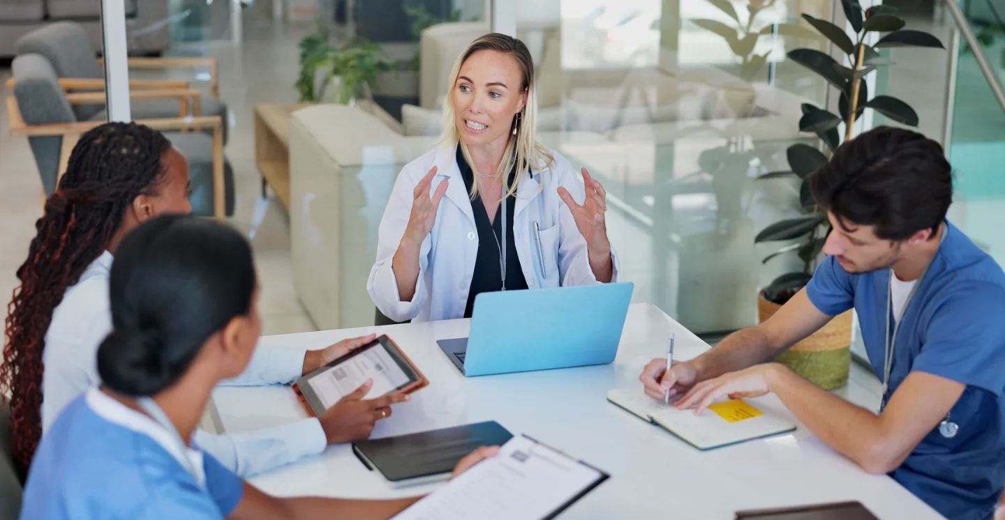Healthcare workers sit around a conference table having a discussion