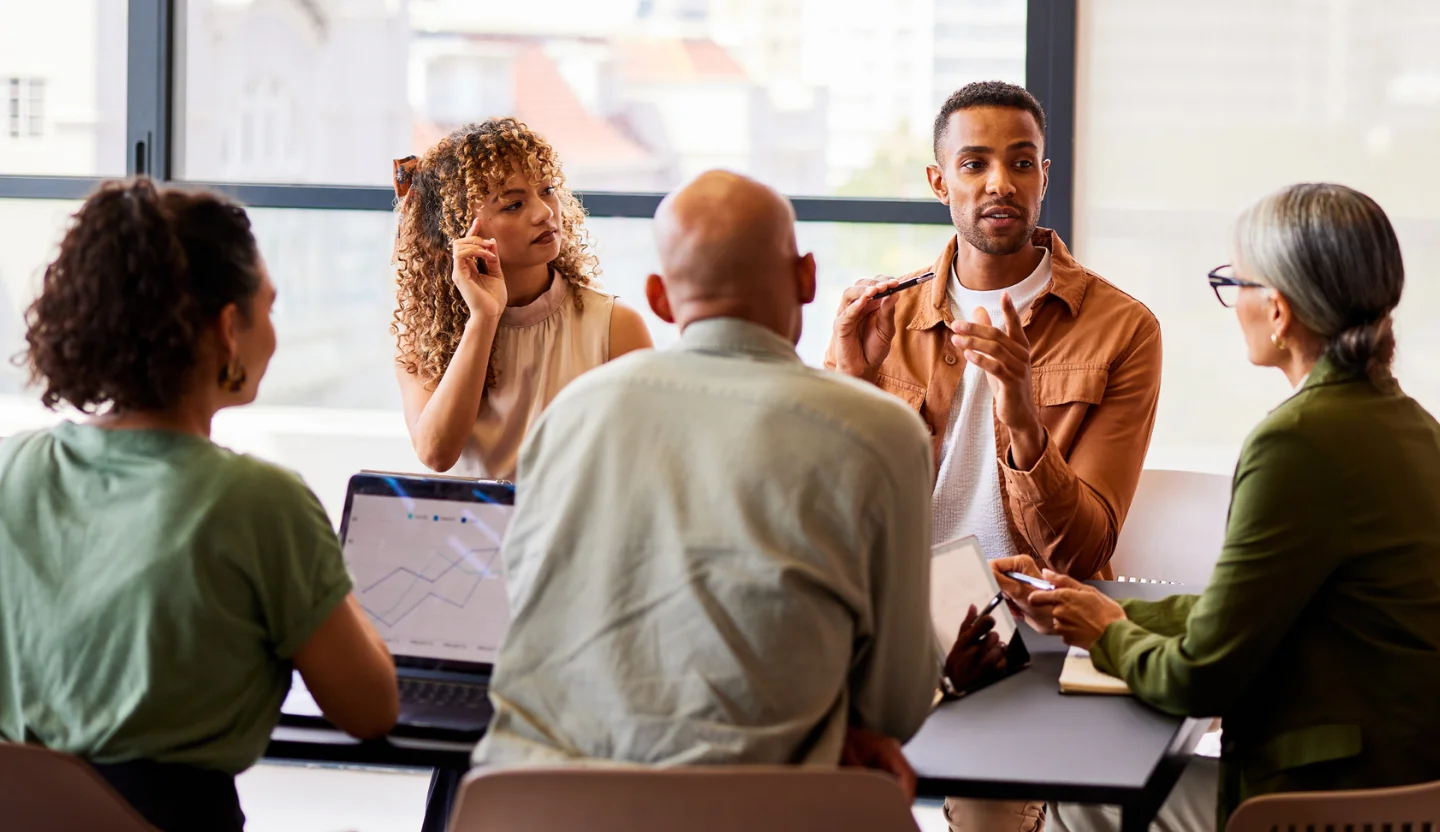 A group of office workers sit around a conference table having a discussion