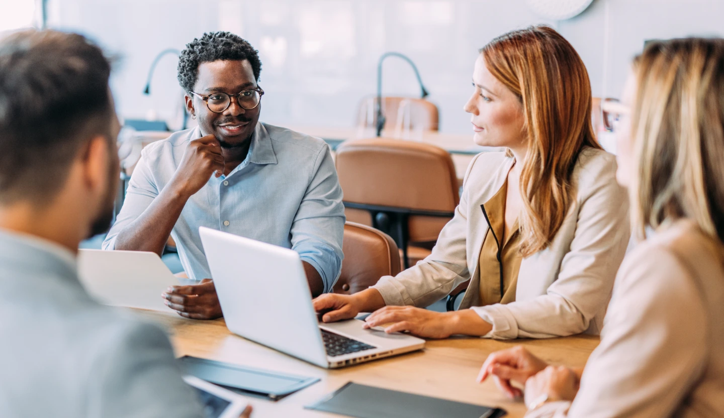 Four office workers sit around a table and have a discussion